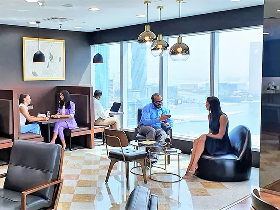 A stylish and welcoming Servcorp business lounge with panoramic city and waterfront views, where professionals are seen networking and relaxing